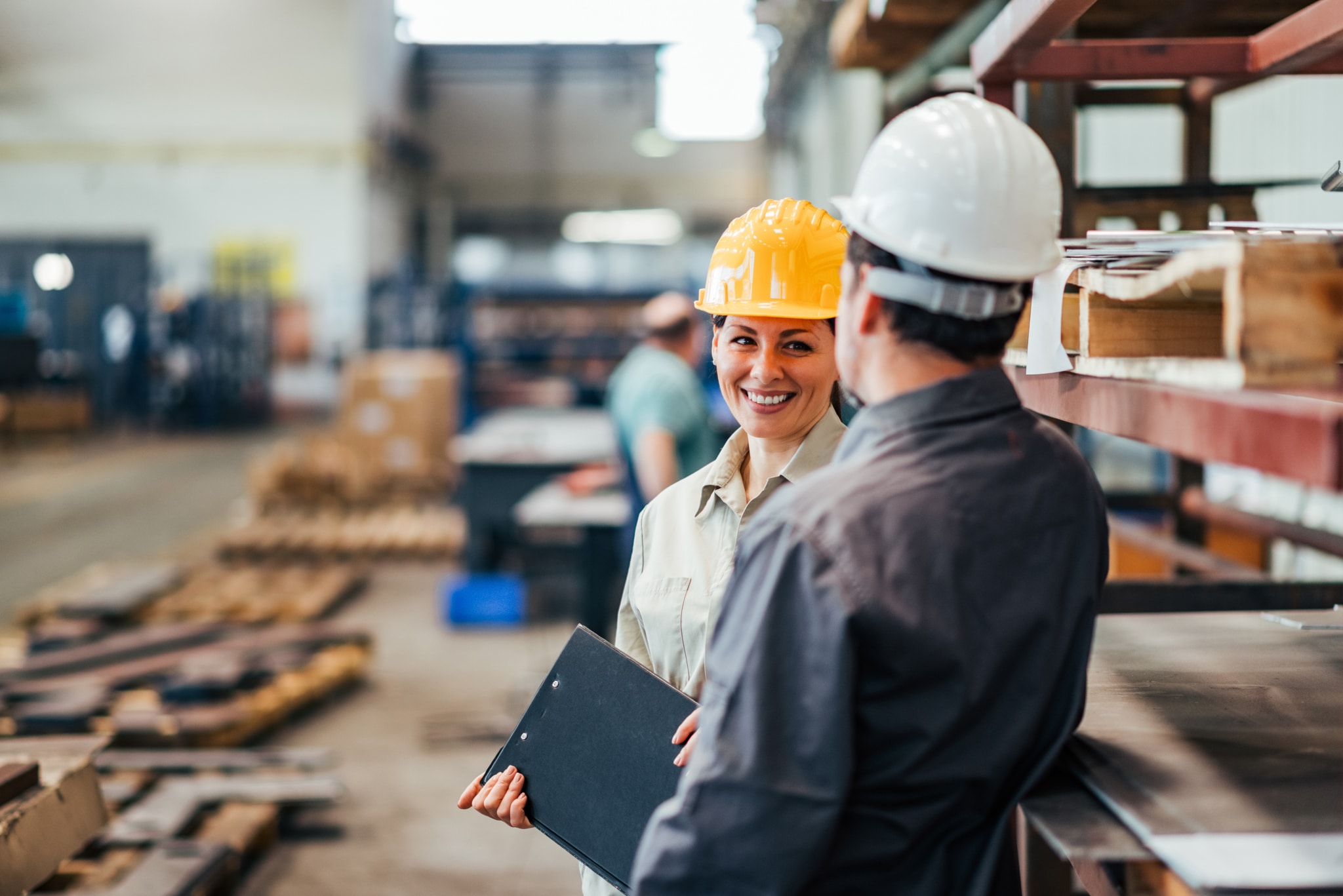 Two people wearing hard hats in a warehouse
