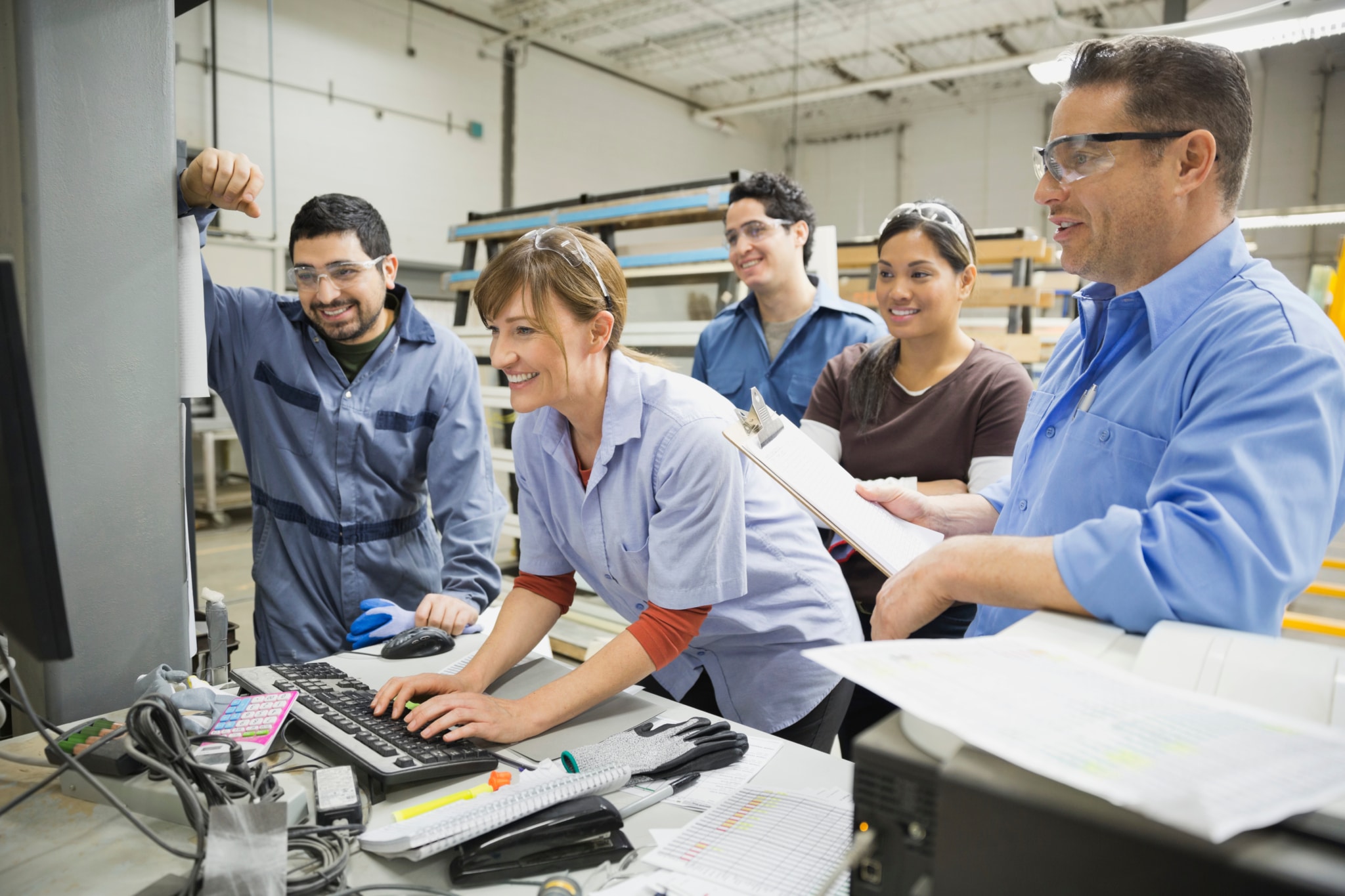 Multiple people working on a desktop in a lumber yard workshop