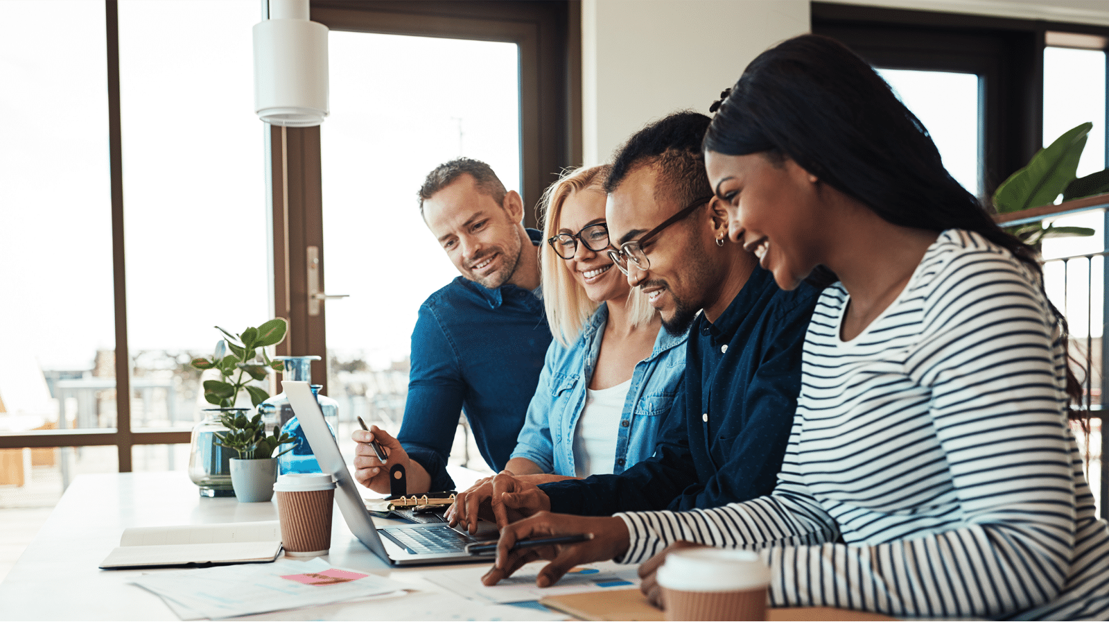 Multiple people smiling working on a laptop together