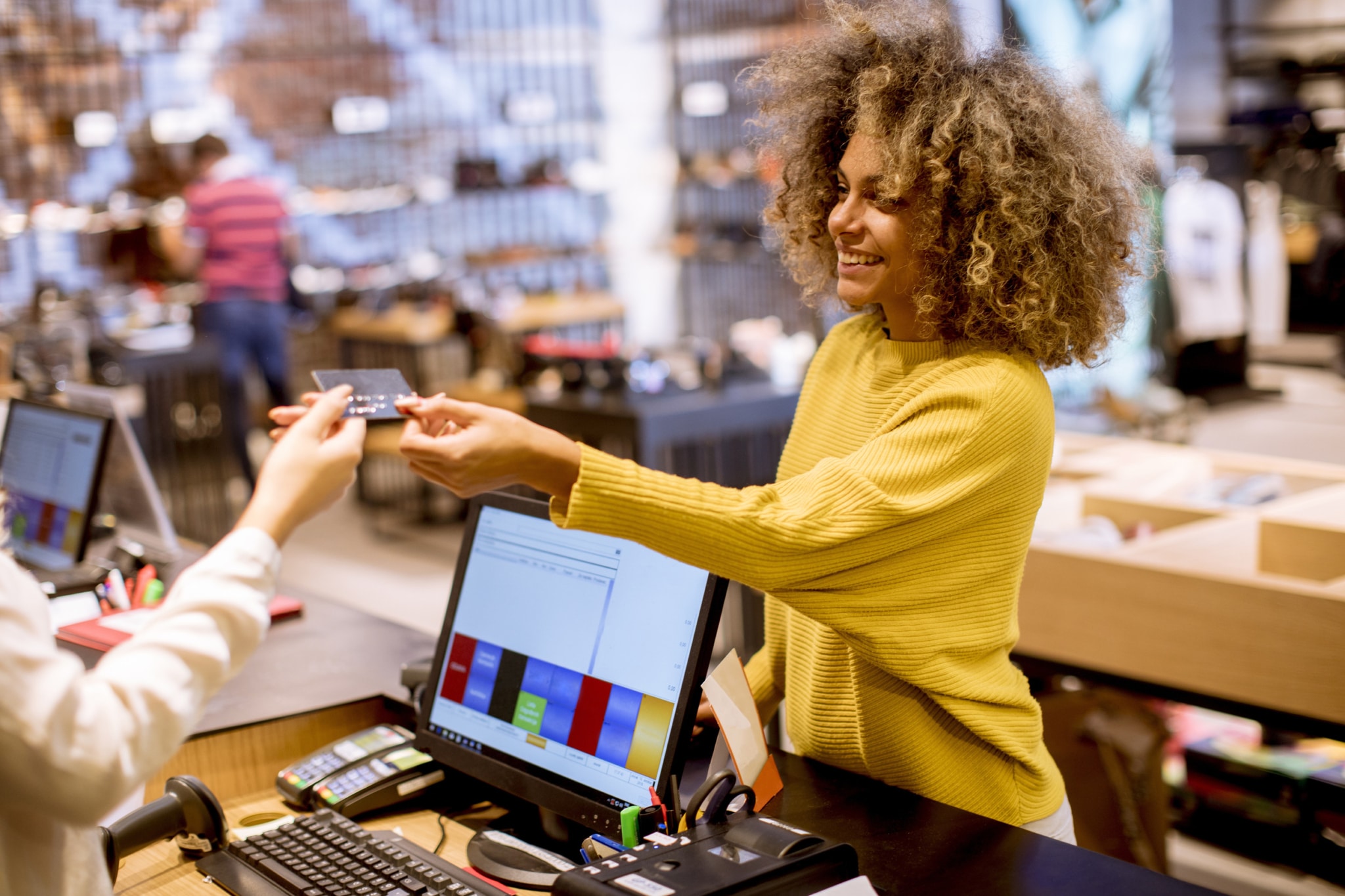 Happy woman customer paying with credit card in fashion showroom