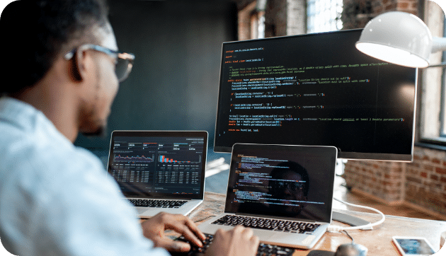 A man in front of three screens