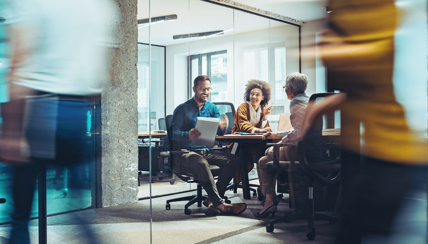 Three people smiling, in a business meeting at an office