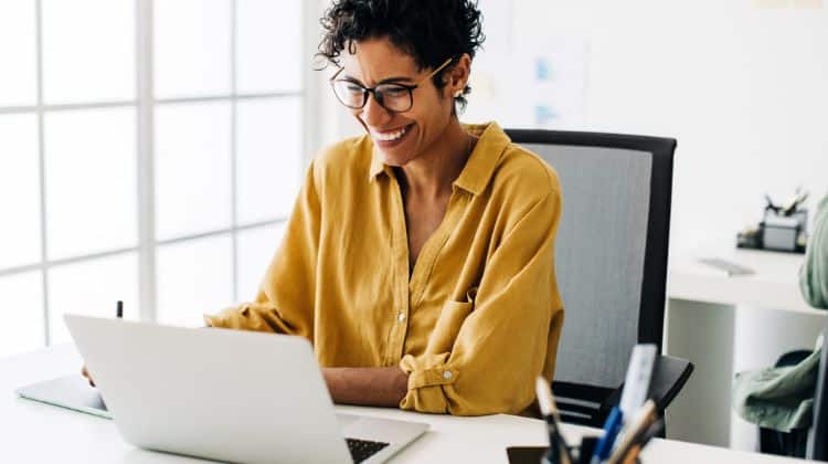 Woman smiling working on a laptop