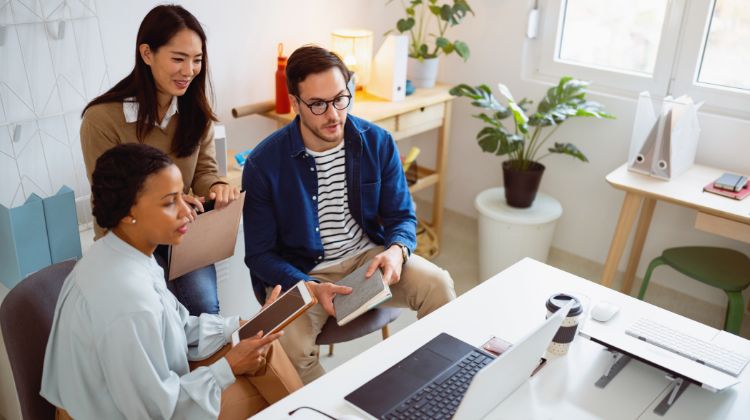 Three coworkers talking together looking at a laptop