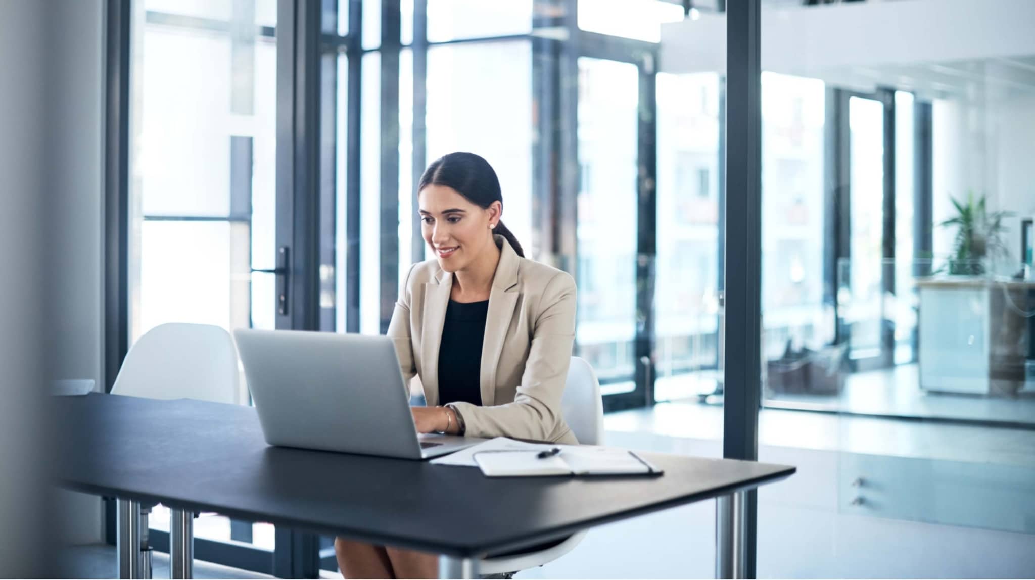 Woman smiling working on a laptop in the office