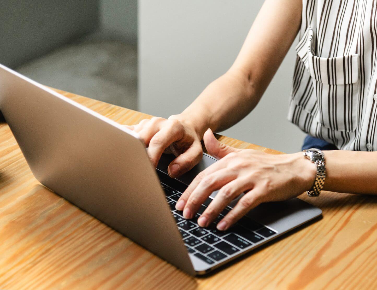 Hands of a woman, typing on a laptop