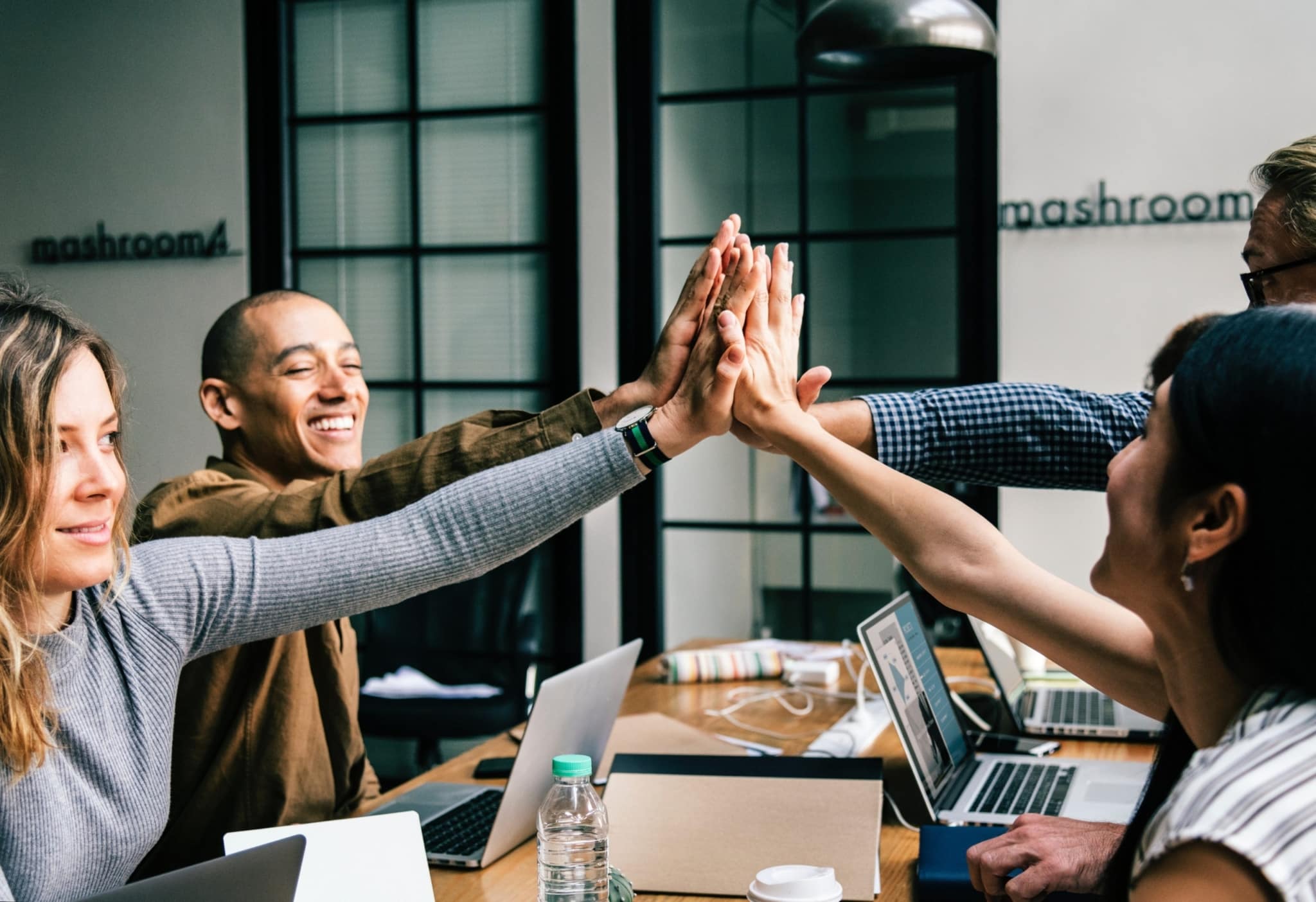 four workers, happy, high-fiving each other