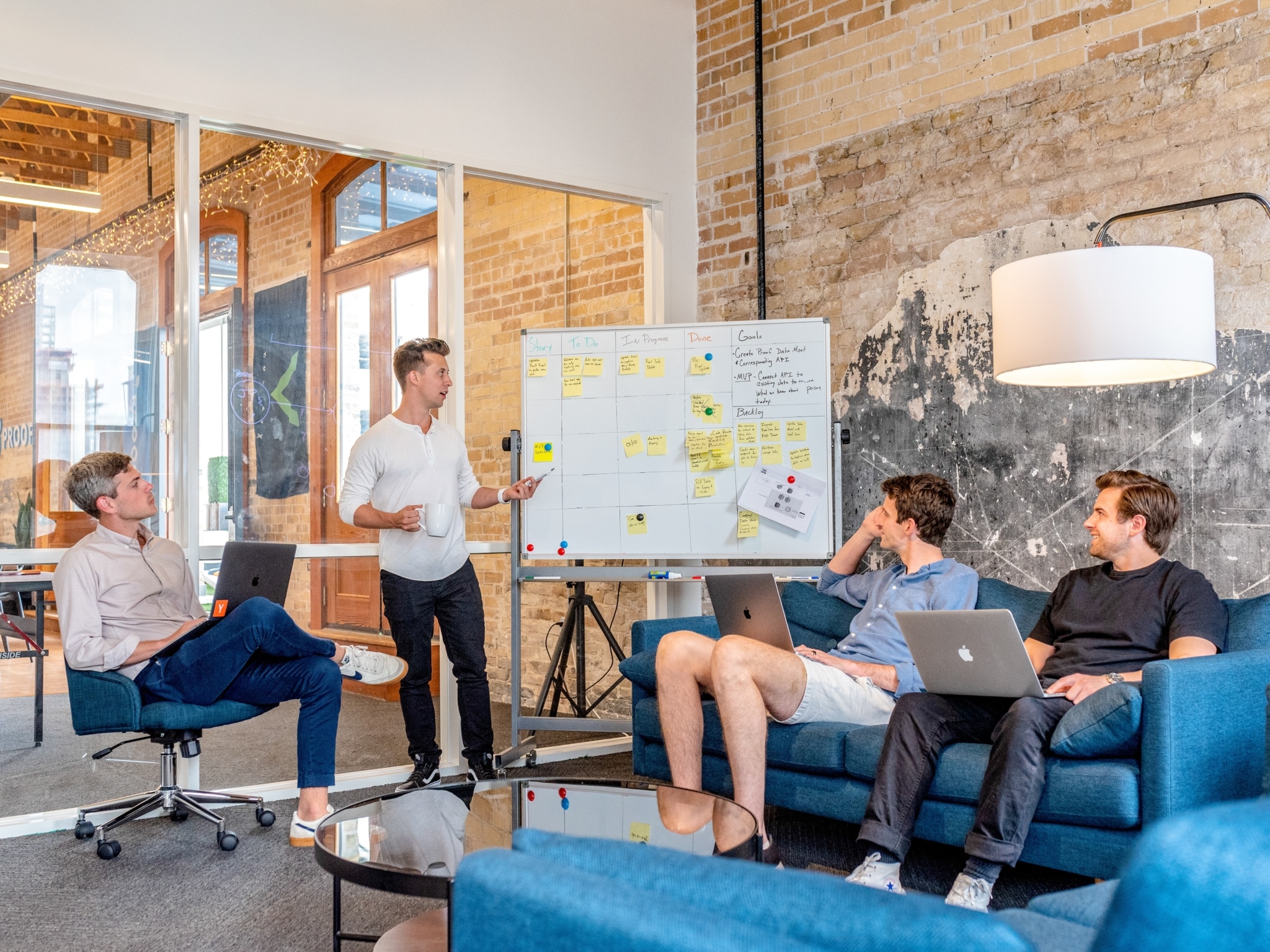 Multiple men working on laptops and drinking coffee during a team meeting