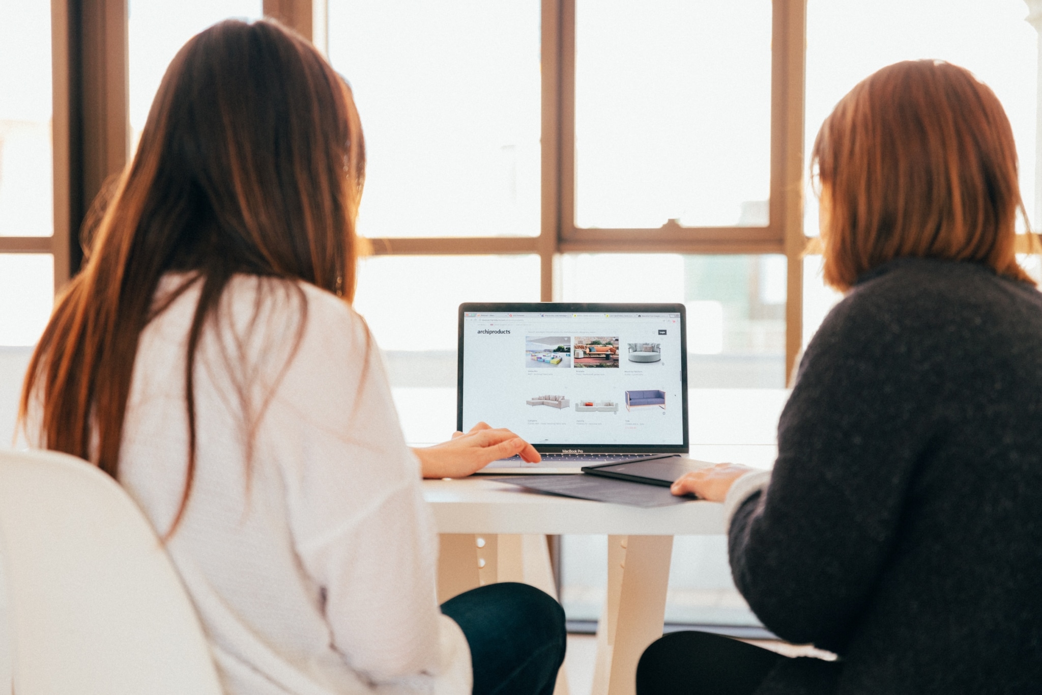 Two women looking up furniture on a laptop