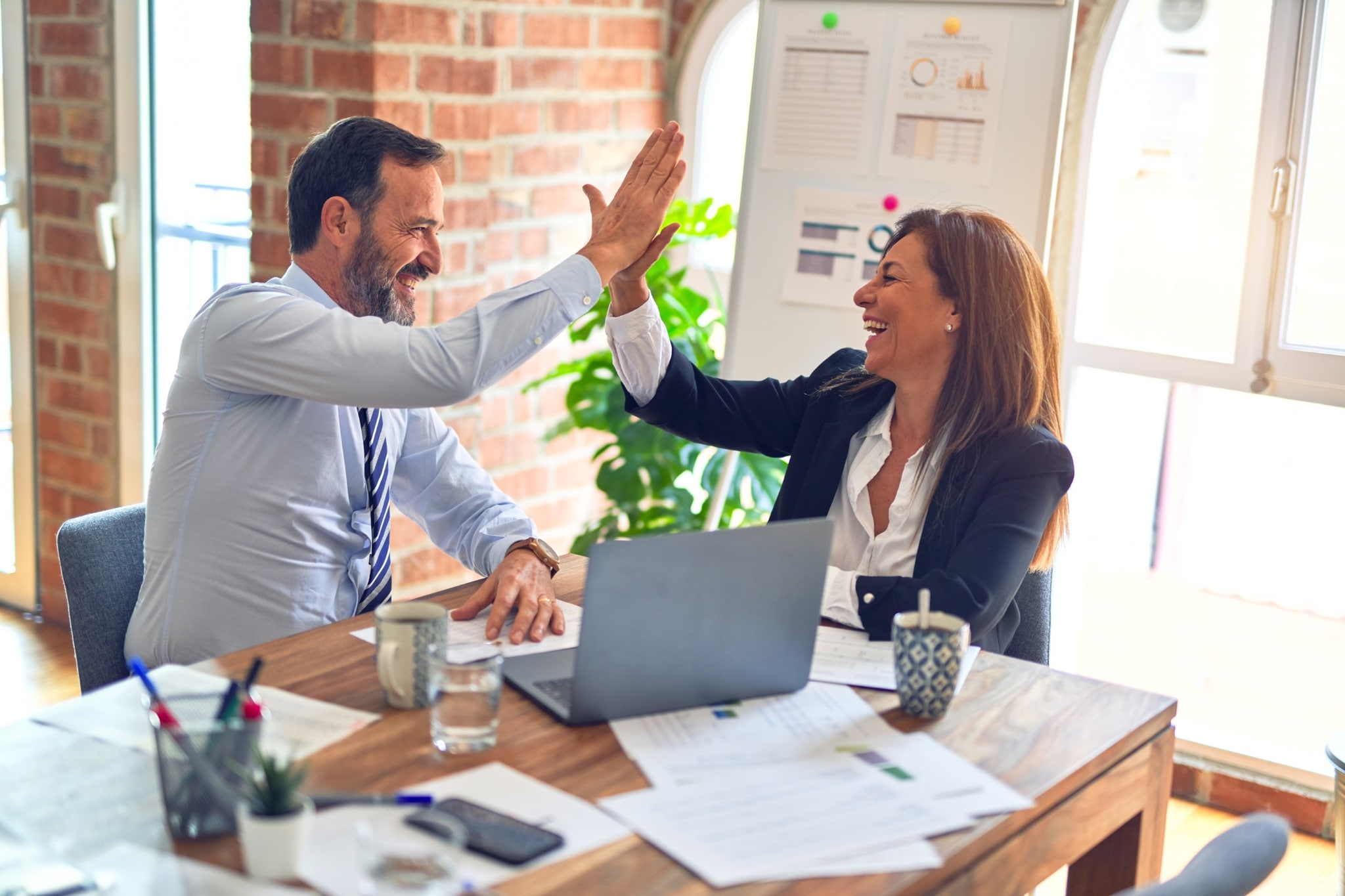 Man and woman co-workers giving each other a high five at the office