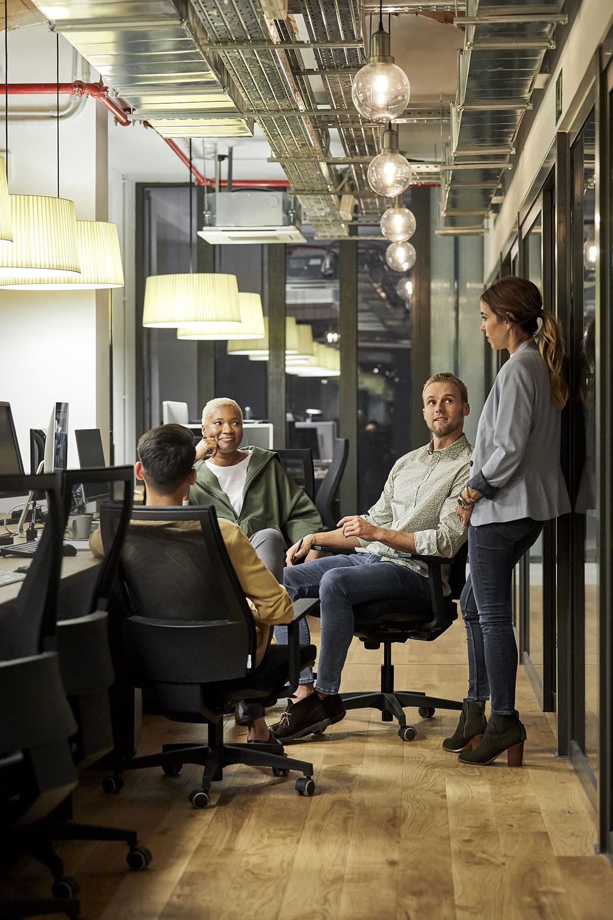 Three people sitting and one woman standing